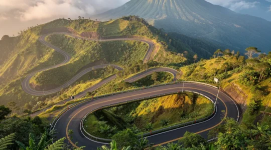 Vue plongeante d'une route de montagne sinueuse avec virages en épingle à cheveux dans un paysage volcanique tropical