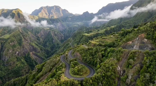 Route sinueuse de montagne avec virages en épingle traversant un canyon tropical verdoyant à La Réunion