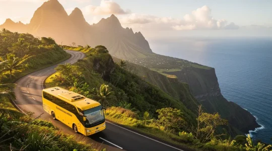 Vue panoramique d'un bus Car Jaune traversant l'île de La Réunion avec l'océan Indien en arrière-plan et les montagnes verdoyantes